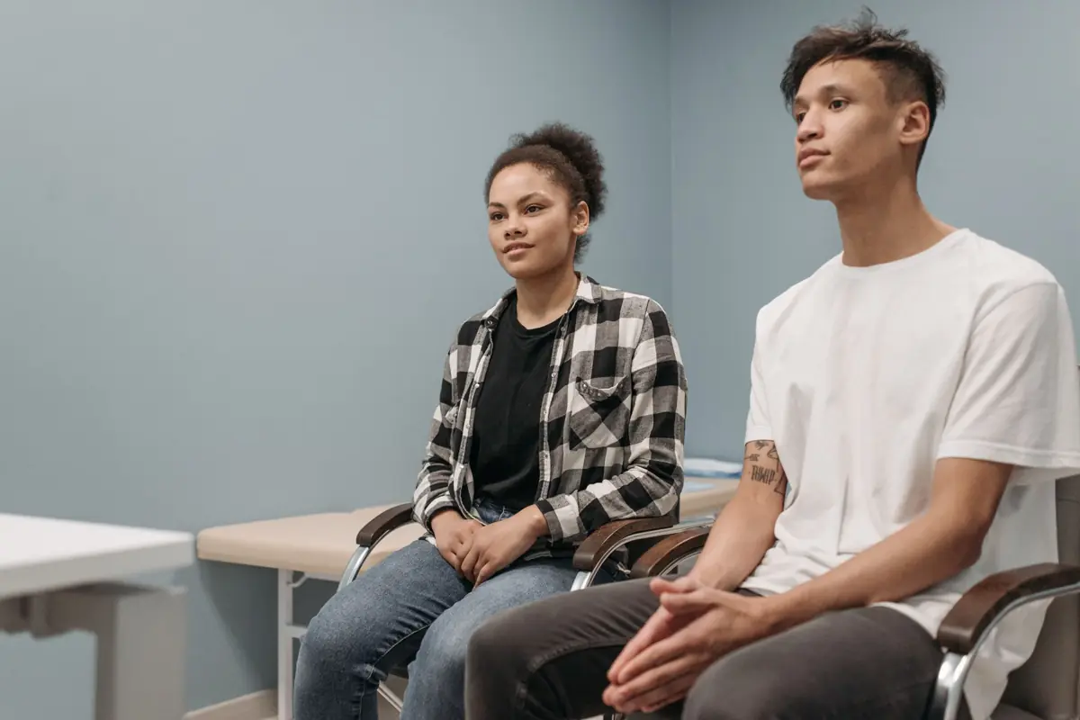 Deux jeunes adultes assis côte à côte dans une salle, en attente