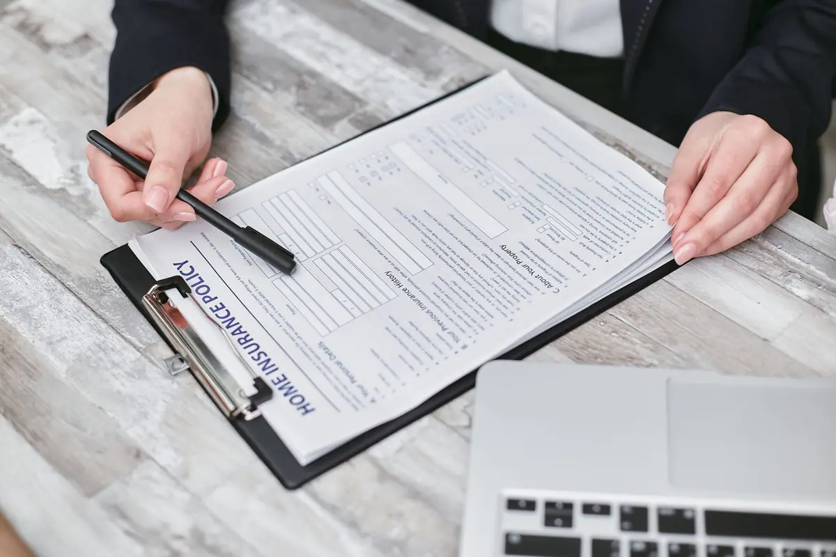 Personne signant un contrat sur un porte-documents posé sur un bureau