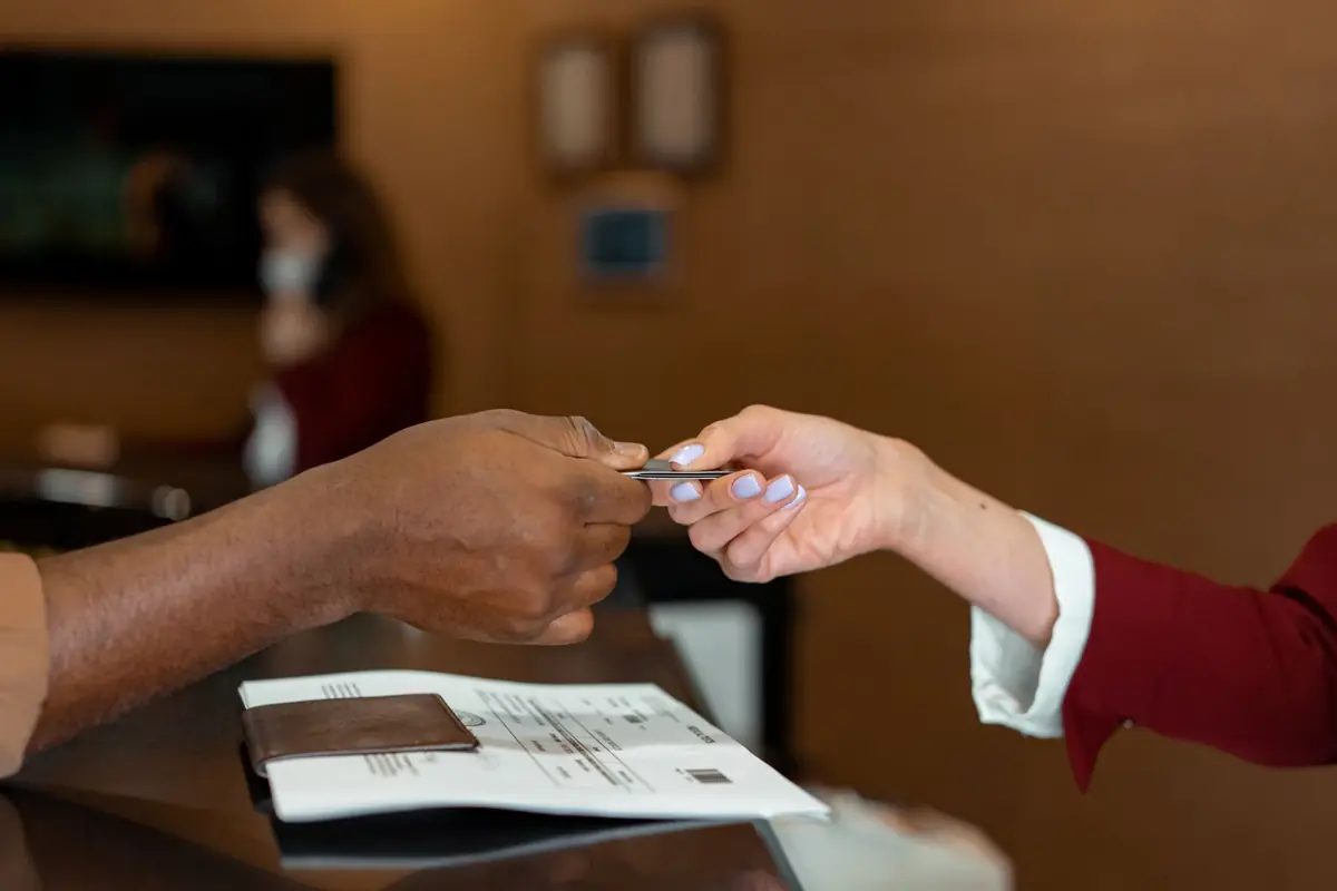 Une main tendant une carte à une autre au-dessus d'un comptoir d'accueil