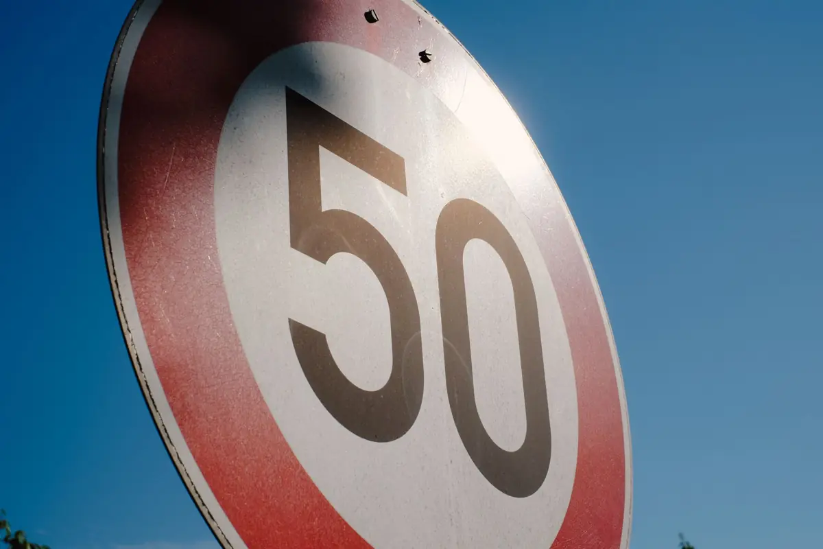 Panneau de limitation de vitesse à 50 km/h vu en contre-plongée sur fond de ciel bleu