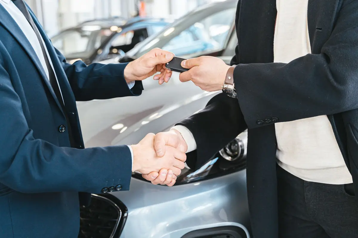 Deux personnes échangeant une poignée de main et des clés de voiture